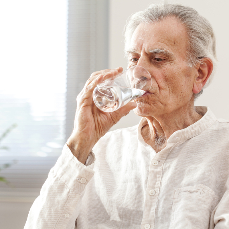An older man drinking a glass of water