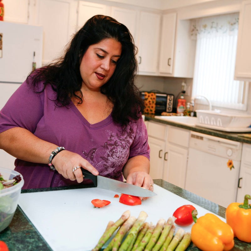 A woman chopping vegetables in a kitchen