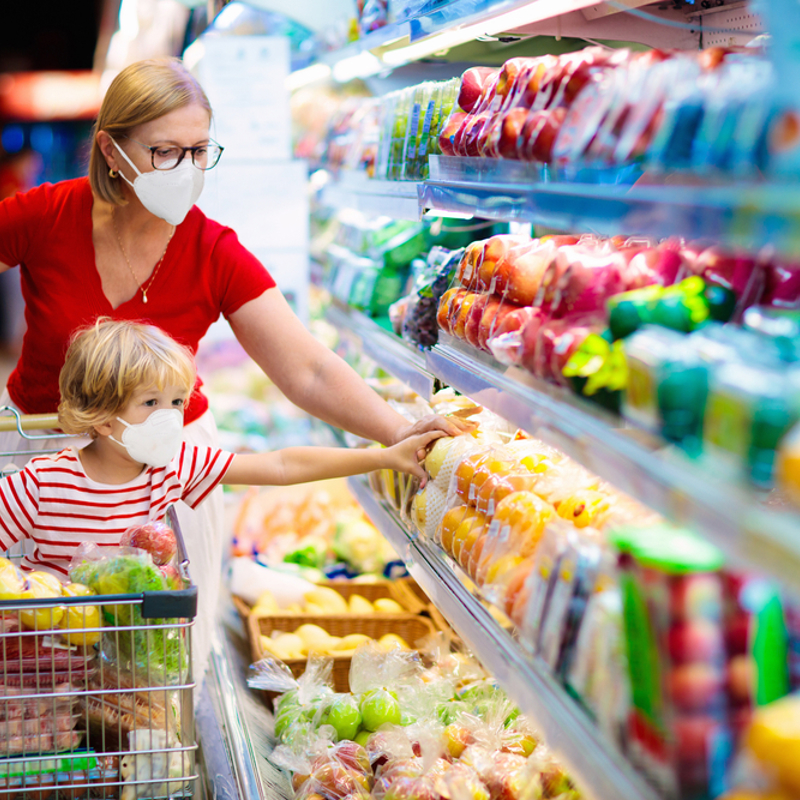 A mum and her child wearing face masks shopping in a supermarket