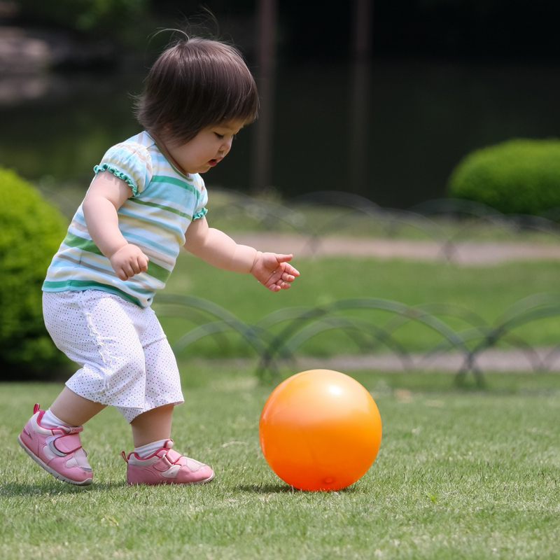 A toddler girl playing with a ball