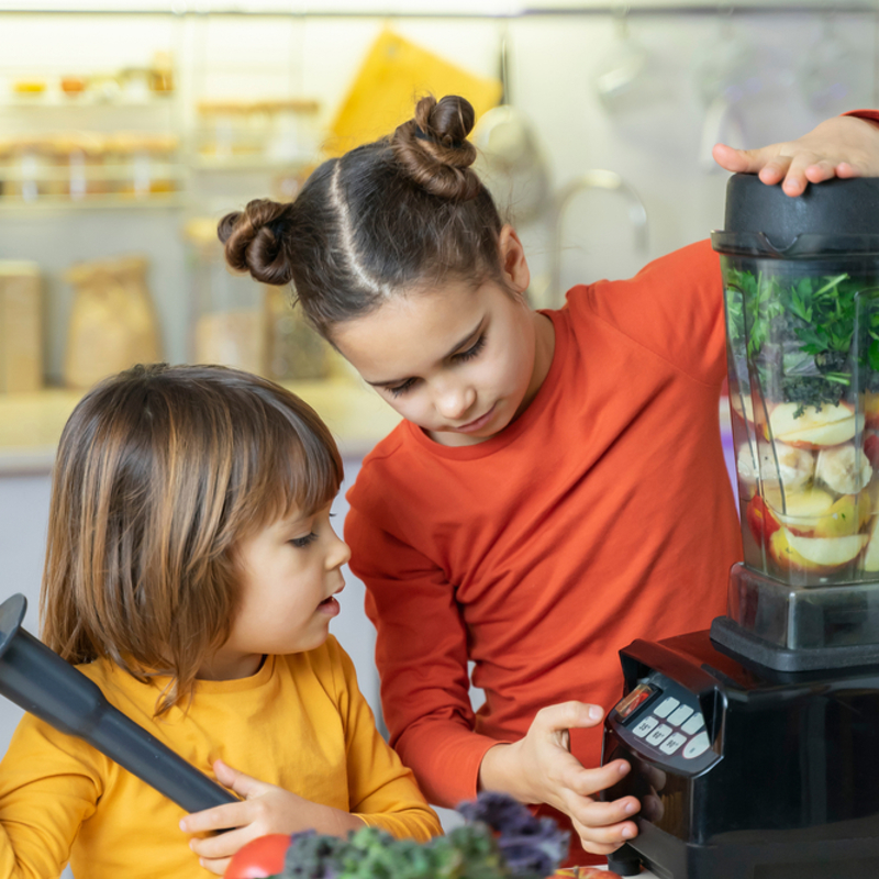 Two children making a smoothie together