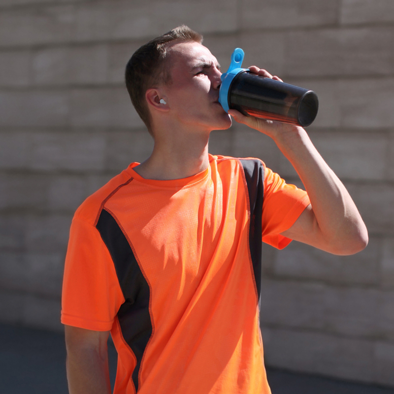 A teenager drinking out of a sports bottle