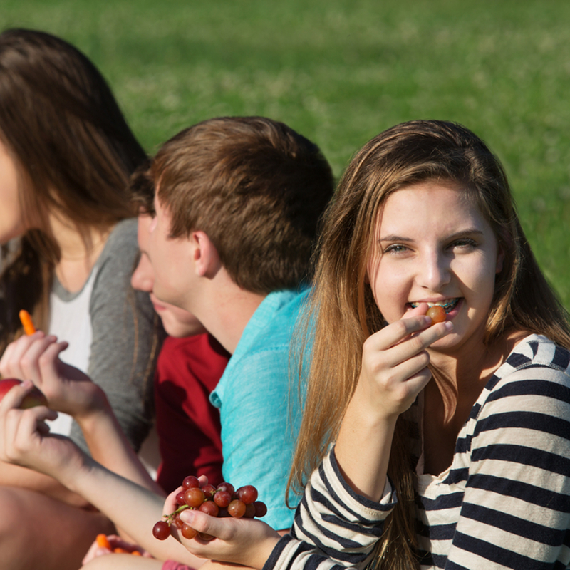 A group of teenagers sat outside eating