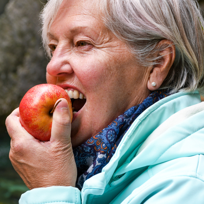 An older woman eating an apple