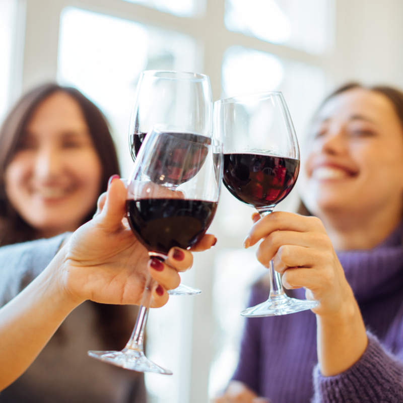 Women drinking red wine and clinking glasses together