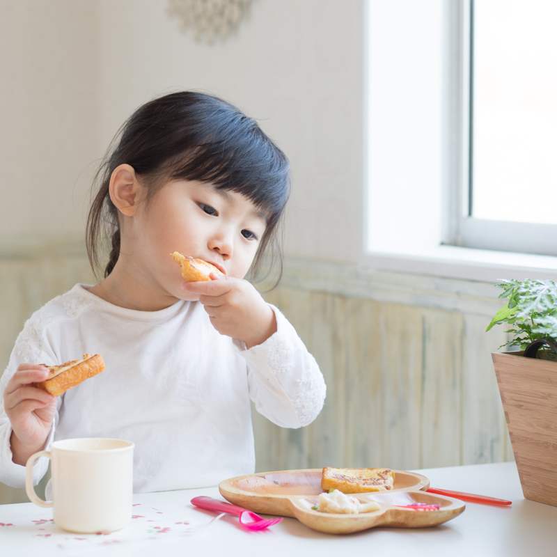 Toddler girl eating food off a plate