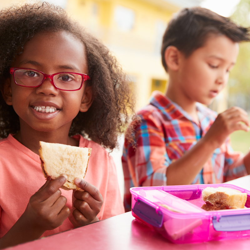 Young children eating packed lunches