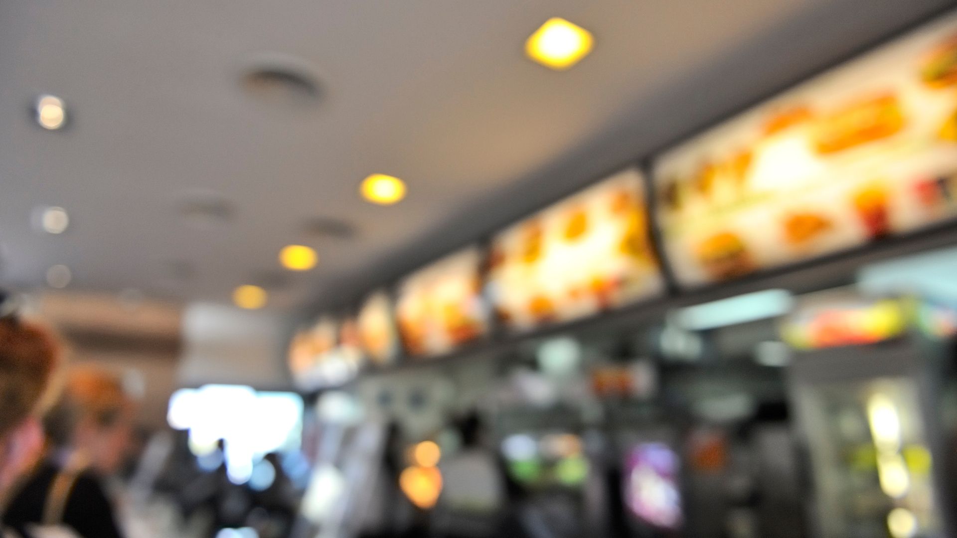 A blurred image of the digital menu in a fast food outlet loading=