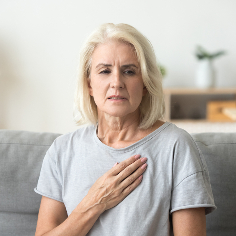 A woman with her hand to her chest in pain