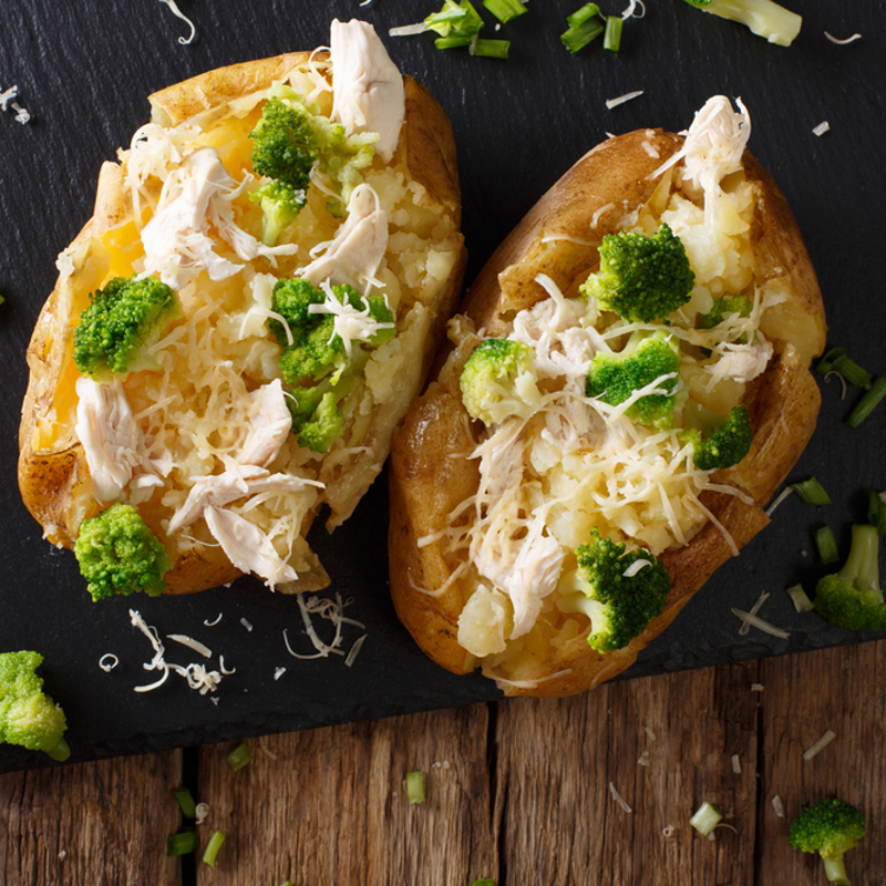A baked potato topped with chicken vegetables and cheese