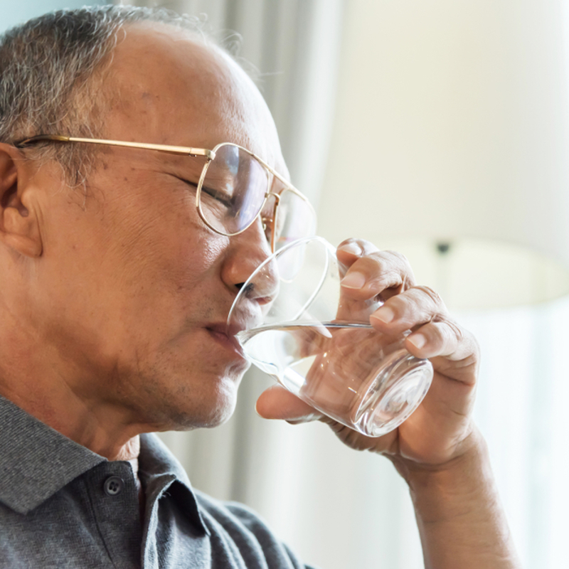 An older man drinking a glass of water