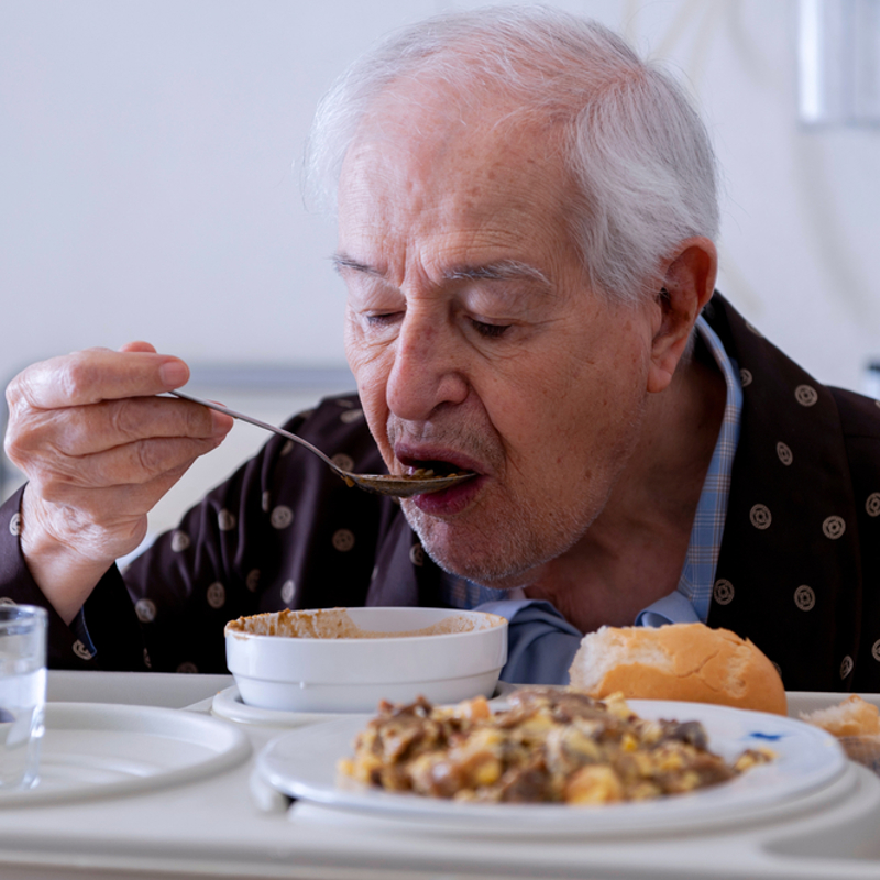 An older man eating a meal in hospital