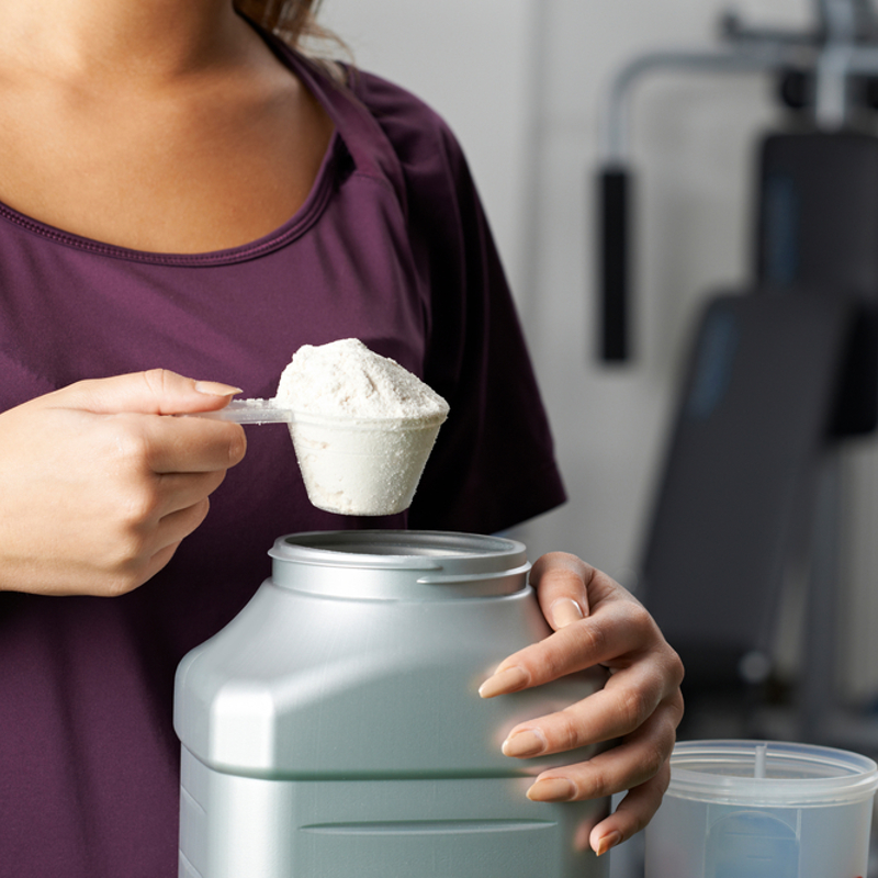 A girl scooping protein powder out of the jar