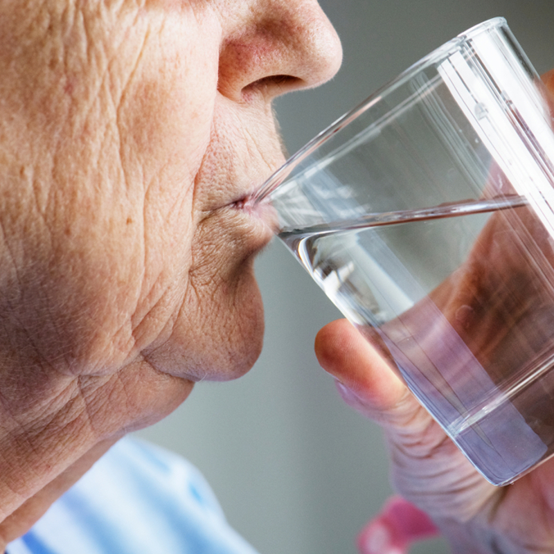Close up of an older man drinking a glass of water