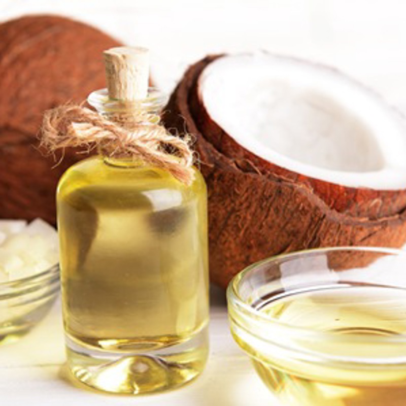 Bottle of coconut oil next to some coconut halves