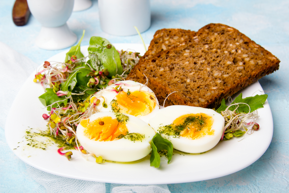 A plate containing a healthy breakfast, featuring wholemeal toast and soft-boiled eggs loading=
