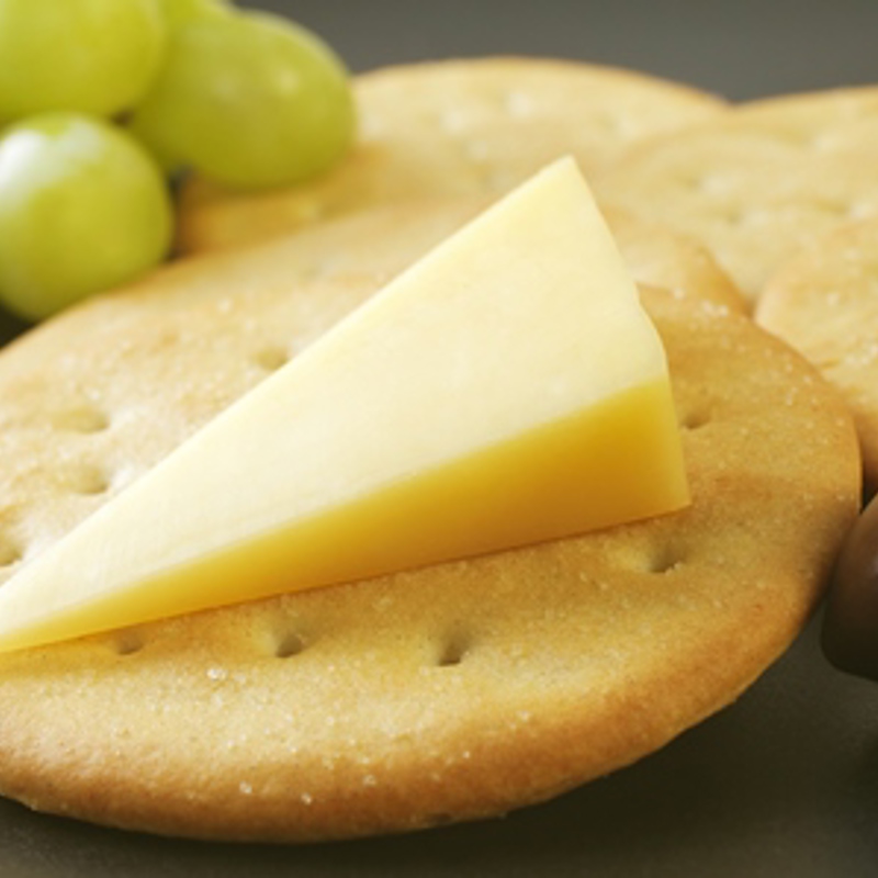 A piece of cheese on a cracker