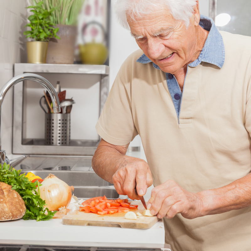 An older man preparing food in the kitchen