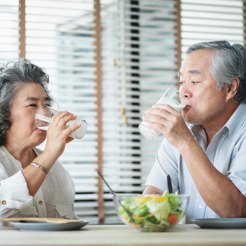 An older woman and man eating and drinking together