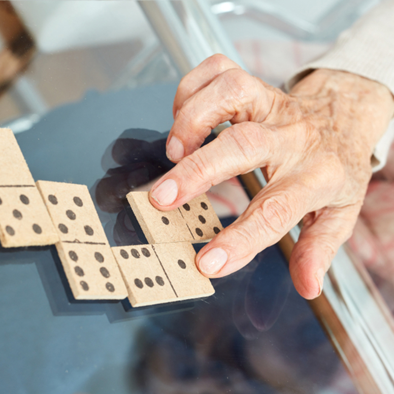 An older adult playing dominoes