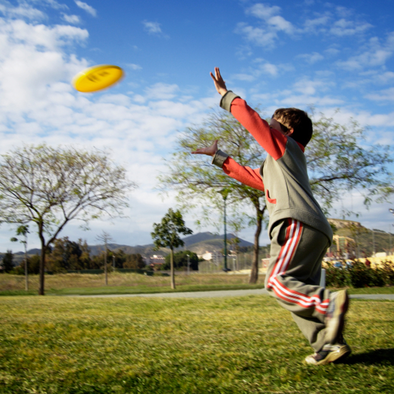A boy playing frisbee in the park