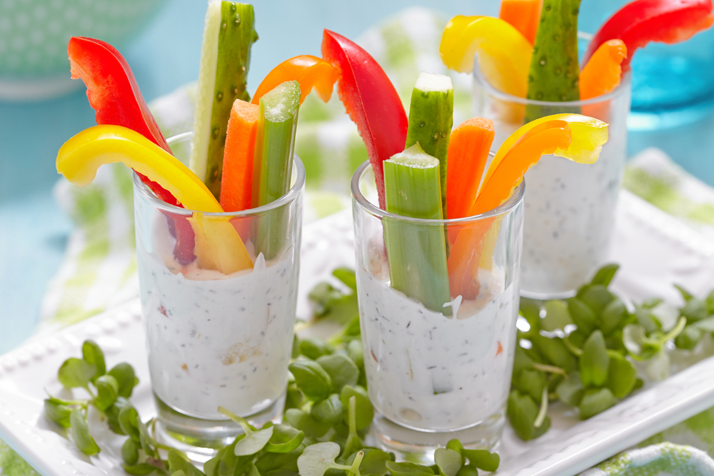 Three glasses filled with a low fat dip and vegetable sticks, including celery and red and yellow peppers loading=