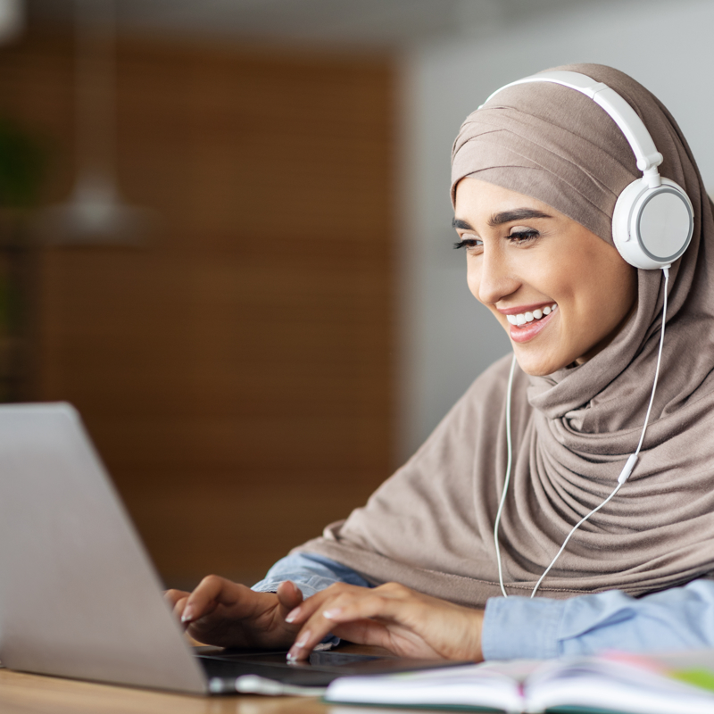 A female student working on a laptop with headphones on