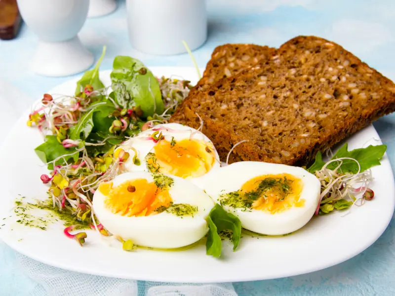 A plate containing a healthy breakfast, featuring wholemeal toast and soft-boiled eggs loading=